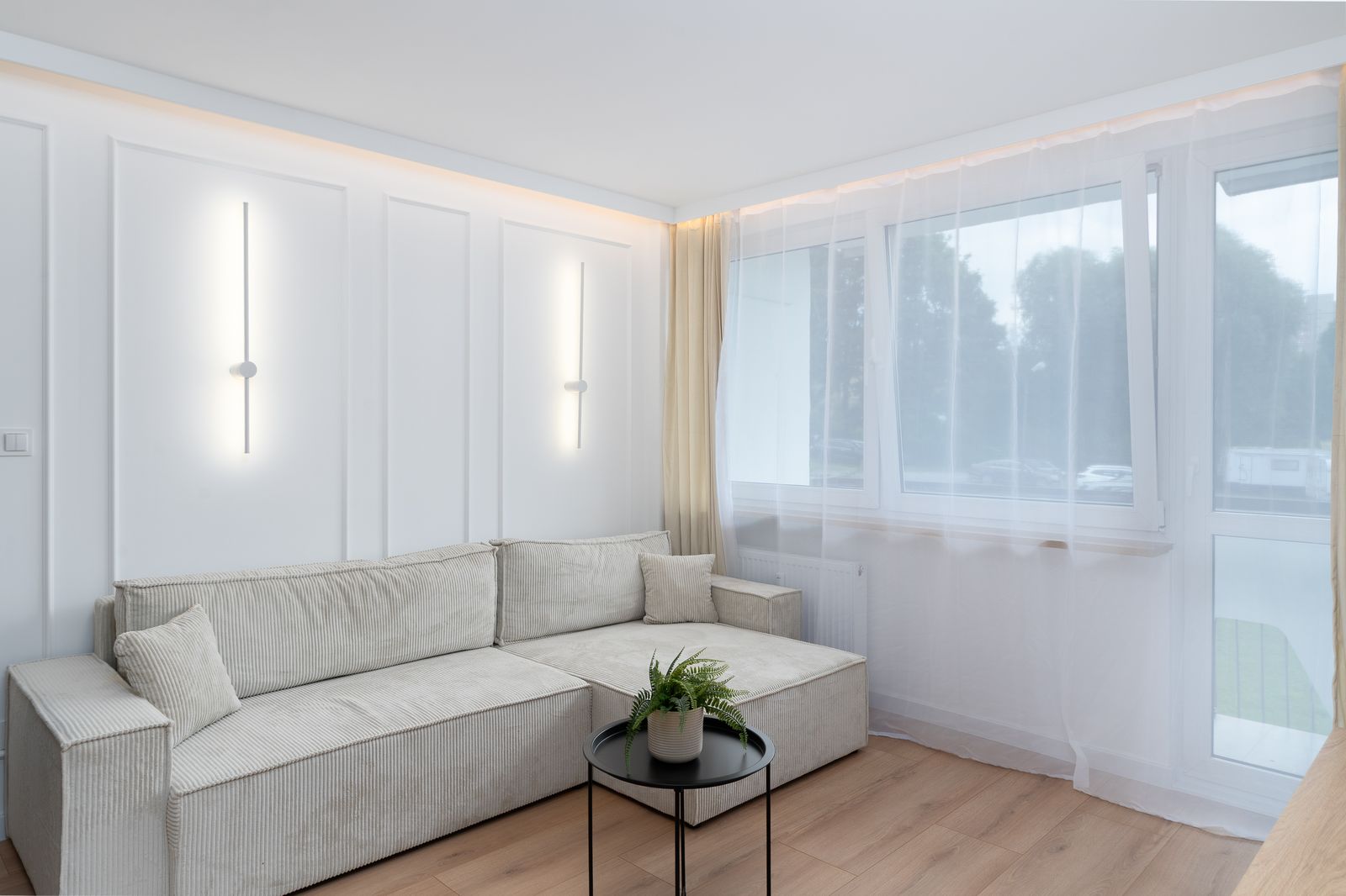 Sunlit minimalist living room with a beige sofa and sheer curtains